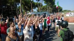 Mani alzate, cantando l'inno di Mameli 250 famiglie di un quartiere di Roma cercano di impedire l'arrivo di 100 migranti, ma vengono dispersi da una polizia inflessibile